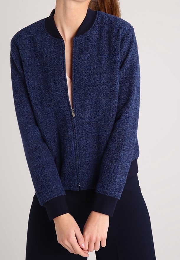 Marineblaue Bomberjacke aus strukturiertem Stoff, mit einem Reißverschluss vorne, geripptem Kragen und Bündchen. Lässiger, kürzer geschnittener Stil.