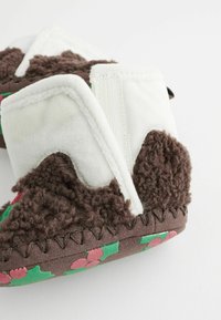 Braune und weiße Hausschuhe mit flauschiger Textur, Blumenmuster auf der Sohle und gesteppten Akzenten. Verfügt über ein weiches, kuscheliges Obermaterial.