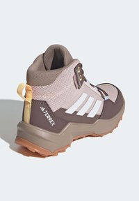 Hnědé a béžové polokozačky na hiking s prodyšným svrchním materiálem, bílými akcentovými pruhy, poutkem a drsnou gumovou podrážkou pro lepší trakci.