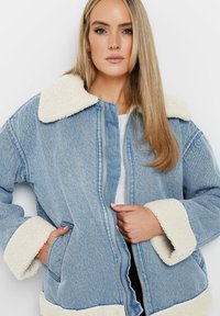 Jeansjacka med en mjuk, krämfärgad syntetpälskrage och manschetter, med dragkedja framtill, avslappnad passform och sidofickor. Ljusblå färg.