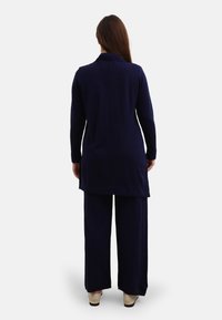 Navy blue long tunic with a collar, paired with wide-leg pants. Both pieces are made of soft, smooth fabric with a relaxed fit.