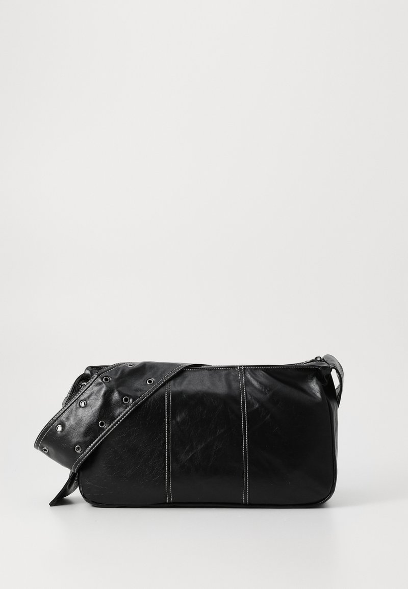 Bolsa de ombro em couro preto com fecho em zíper, apresentando um corpo texturizado, costura branca e uma alça com ilhós prateados.
