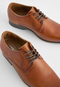 Chaussures de ville en cuir marron avec une surface lisse, un orteil rond et un laçage à cinq œillets. Comprend des lacets marron et une semelle intérieure texturée.