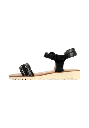Sort flad sandal med ankelrem, flettet frontrem med sølvpynt og beige gummisål med mønster for greb.