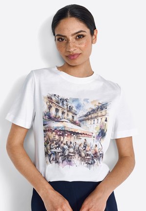 T-shirt en coton blanc avec une scène imprimée en aquarelle d'un café avec des sièges extérieurs, montrant des gens et des détails architecturaux.