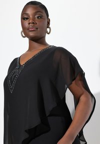 Schwarzes Chiffon-Top mit transparenten Ärmeln, V-Ausschnitt und verziertem Strass-Detail entlang des Ausschnitts. Glatte Textur, lockere Passform.