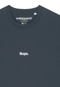 Navyblauwe katoenen t-shirt met een ronde hals. In het midden staat er witte tekst "Nope." Het etiket binnenin toont het merk en de onderhoudsinstructies.