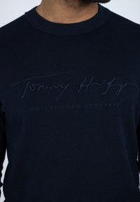 Granatowa bluza wykonana z bawełny, z wypukłym logo w tym samym kolorze oraz okrągłym dekoltem i prążkowymi mankietami.