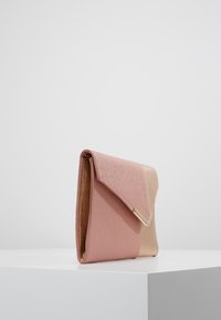 Růžová a zlatá psaníčková kabelka s texturovaným povrchem, trojúhelníkovým uzávěrem a metalickými akcenty. Plochý, obdélníkový tvar.