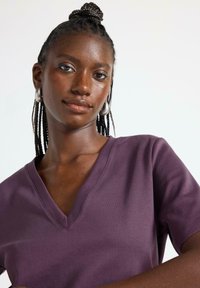 V-hals t-shirt i dyb lilla bomuldsstof med korte ærmer. Glat struktur, tætsiddende design og en naturlig halsudskæring.