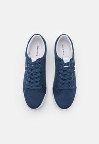 Scarpe da ginnastica in tela blu navy con suole in gomma bianca, punta rotonda e lacci piatti. Presentano un piccolo logo sul lato e un design classico.