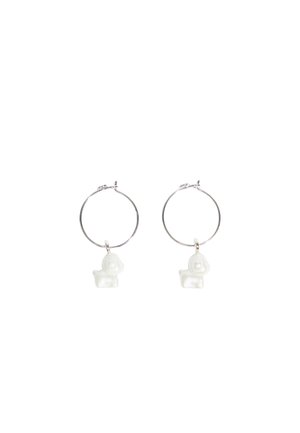 Orecchini a cerchio in argento con charm a forma di cane bianchi e lucidi, caratterizzati da texture lisce e forme rotonde. Design semplice e giocoso.