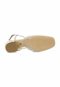 Sandale à talons hauts beige avec une tige en cuir lisse, une bride de cheville réglable et une semelle en caoutchouc texturée, présentant un bout rond.