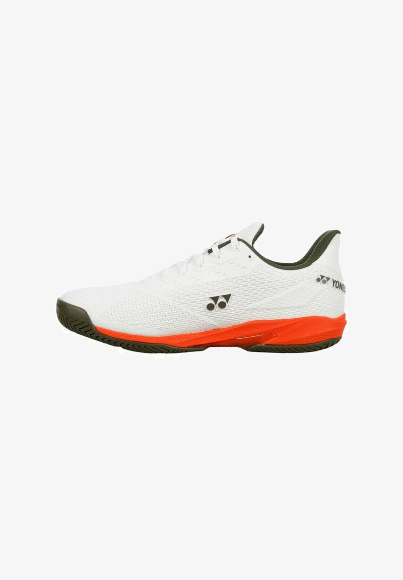 Chaussure de sport basse blanche avec une semelle intermédiaire orange, une semelle noire et un logo Yonex noir sur le côté et le talon.