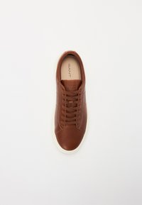 Brauner Leder-Sneaker mit glatter Oberfläche, runder Zehenpartie, weißer Gummisohle und kontrastierenden Schnürsenkeln. Markenlogo auf der Zunge.