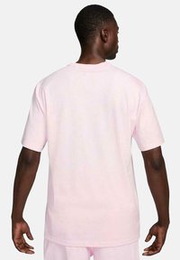 Camiseta de algodón rosa claro, de mangas cortas, corte relajado, escote redondo, textura suave y diseño limpio y sencillo sin logotipos ni patrones visibles.