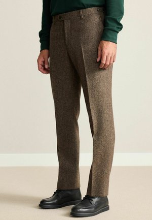 Brown textured wool trousers with a straight leg design, featuring a flat front, side pockets, and button closure. Paired with black shoes.