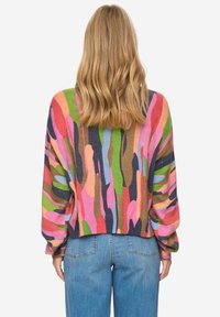 Jersey tejido colorido con un audaz patrón abstracto en rosa, verde, azul y marrón. Cuenta con un diseño de hombros caídos y un dobladillo acanalado.