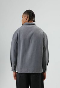 Grijze overshirt van een wollen mix met een losse pasvorm, brede kraag en knoopmanchetten. Heeft een zachte textuur en een minimalistisch ontwerp.