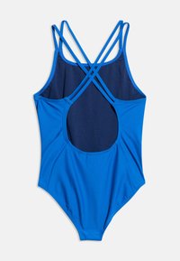 Ολόσωμο μπλε μαγιό με λεπτούς διασταυρωμένους ιμάντες στους ώμους και μεγάλο ανοιχτό άνοιγμα στην πλάτη.