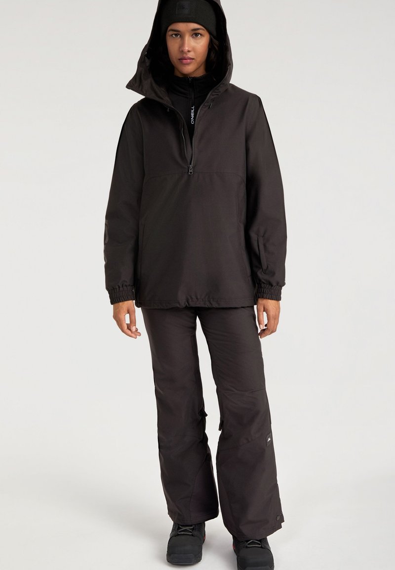 Conjunto de abrigo negro que incluye una chaqueta de pull con cremallera frontal y puños elásticos, acompañada de pantalones de corte holgado. Textura suave, diseño práctico.