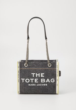 Grå denim totebag med sølvkjede og lærhåndtak. Har hvit tekst og gule sidestriper. Rektangulær form med solid design.