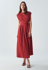 Červené maxi šaty s krátkými rukávy a pásem v pase. Vyrobené z texturované látky, s hladkým povrchem a volným střihem.