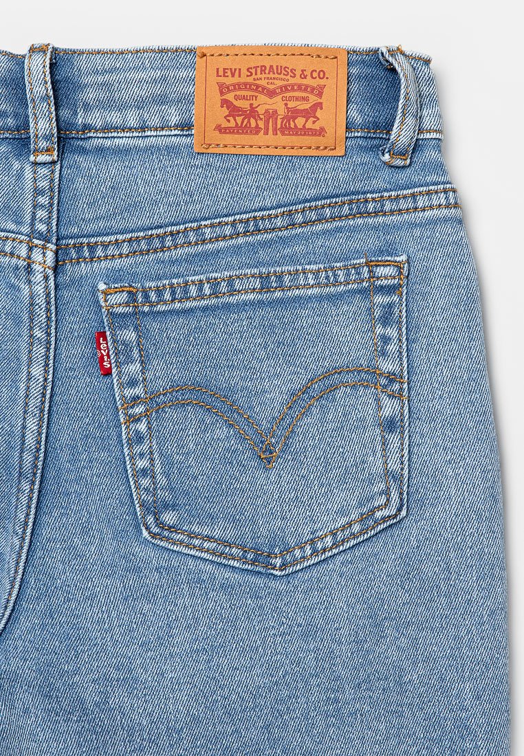 Blaue Denim-Jeans mit sichtbar aufgesetzten Gesäßtaschen, rotem Levi's-Logoschild und einem beigefarbenen Lederpatch von Levi Strauss & Co. am Bund.