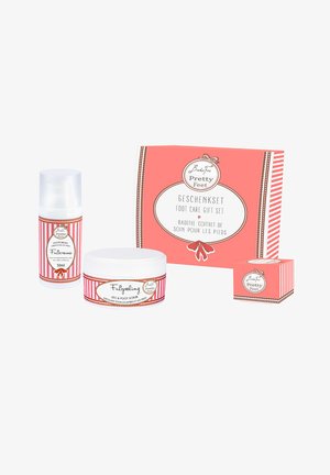 Fußpflege Geschenkset in einer rosa Box, das eine Fußcreme, ein Fußpeeling und einen kleinen Behälter enthält. Alle Artikel haben dekorative Etiketten mit abwechselnden Streifen.