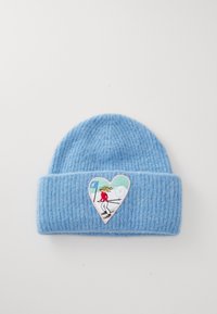 Blue knitted beanie with a folded hem, featuring a heart-shaped embroidered patch of a skier in red attire against a light blue background.