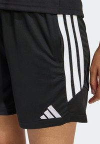 Μαύρο αθλητικό σορτς με λευκό σχέδιο τριών ρίγες στο πλάι, με υφή και μικρό λογότυπο στη ραφή.