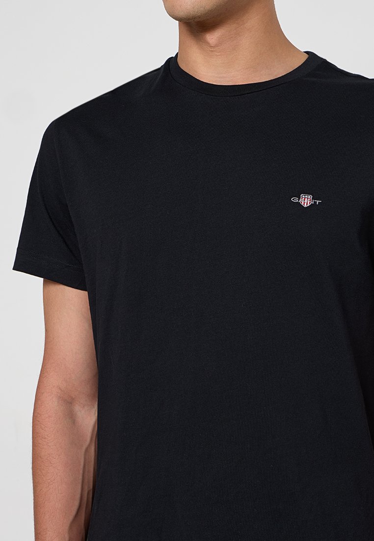 Czarna koszulka z krótkim rękawem wykonana z bawełny, z okrągłym dekoltem i małym logo na piersi. Gładka tekstura, klasyczny design.