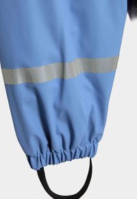 Tessuto impermeabile blu con polsino arricciato, caratterizzato da una striscia riflettente argento. Include un anello nero per attacco o sospensione.
