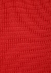 Roter strukturierter Stoff mit einem gerippten Muster, das kleine, quadratische Eindellungen auf der gesamten Oberfläche zeigt und einen erhabenen Effekt erzeugt.