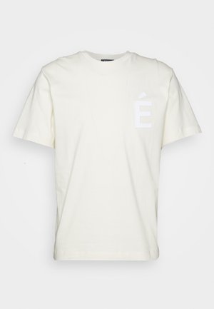 Cremefarbiges Baumwoll-T-Shirt mit kurzen Ärmeln, das ein weiß bedrucktes "É"-Logo im linken Brustbereich trägt.