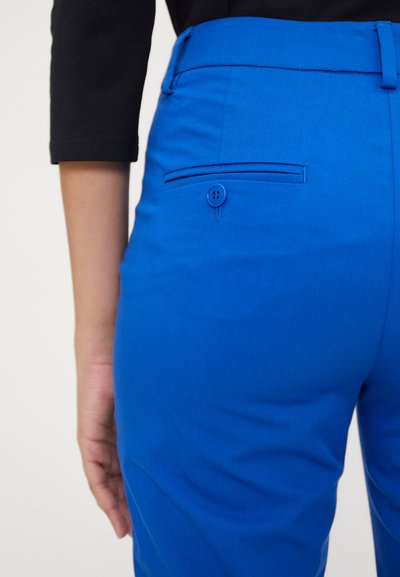 Des pantalons ajustés bleu vif qui présentent une coupe slim, une texture lisse, une poche arrière avec une fermeture à bouton plat et une finition de taille propre.