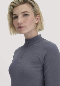 Grauer gerippter Oberteil mit hohem Kragen und halbem Reißverschluss. Enganliegendes Design mit Nahtdetails, das eine glatte Textur und eine schlanke Silhouette präsentiert.
