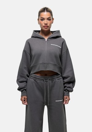 Grijze cropped hoodie met oversized mouwen, een rits aan de voorkant en een logo. Gecombineerd met bijpassende grijze sweatpants met elastische taille en logo-detail.