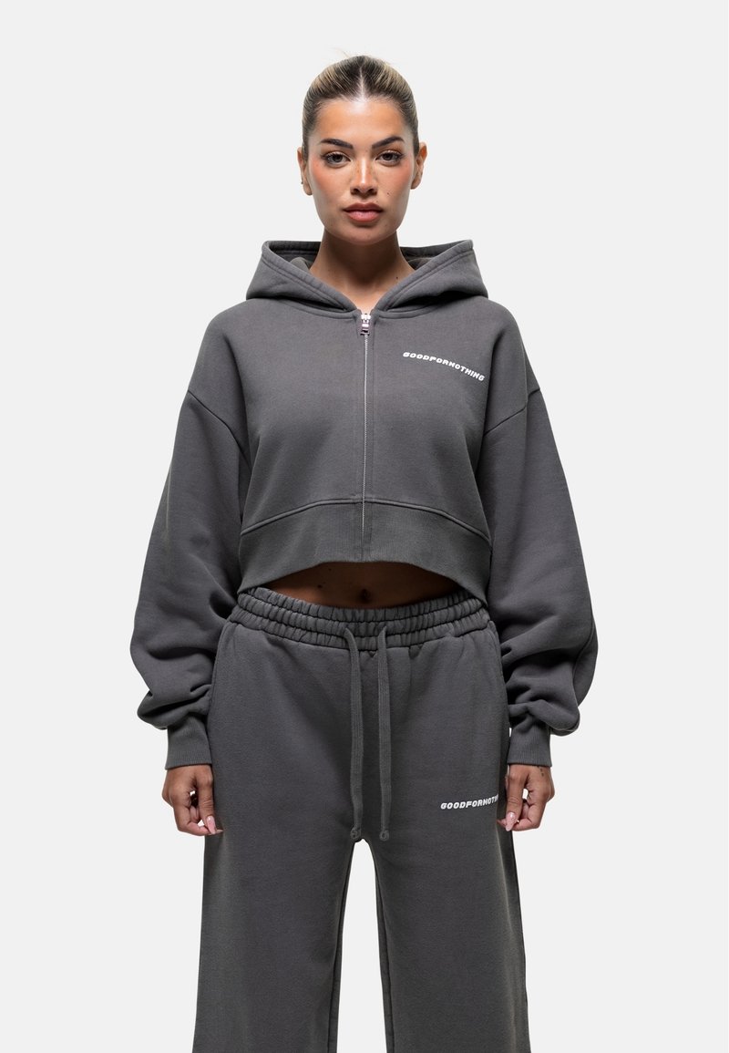 Grijze cropped hoodie met oversized mouwen, een rits aan de voorkant en een logo. Gecombineerd met bijpassende grijze sweatpants met elastische taille en logo-detail.