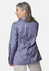 Hellpurpurnes Jacket mit strukturiertem Finish, strukturiertem Kragen und sichtbaren Nähten; getragen mit neutralen Hosen.