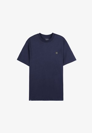 T-shirt bleu marine à manches courtes en coton. Présente un petit graphisme vert sur la zone gauche de la poitrine. Encolure ronde basique.