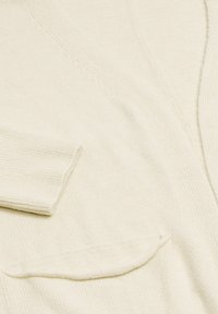 Cardigan color crema con una tessitura morbida, caratterizzato da un collo a V, polsini a coste e una tasca sul lato sinistro.