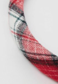 Červená a bílá kostkovaná látková čelenka s jemným povrchem; obsahuje černé a šedé detaily v designu, kulatý tvar.