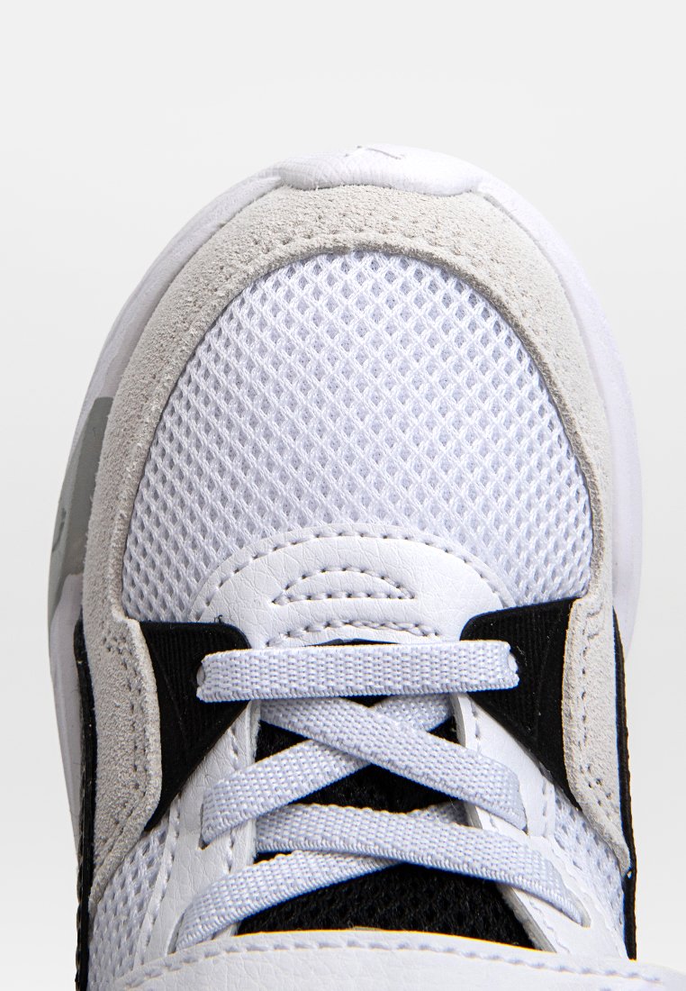 Witte sportieve schoen van mesh en suede materialen, met zwarte accenten, een ronde teen en platte veters. Glad textuur op de leren delen.