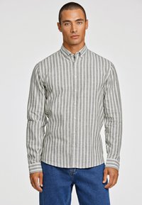 Grijs en wit gestreepte overhemden met lange mouwen, voorzien van een kraag en rechte zoom, gecombineerd met blauwe denim broek.