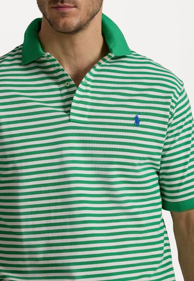 Camisa polo verde e branca com riscas, com gola e mangas curtas, apresentando um pequeno logótipo azul no peito. Material de algodão.