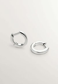 Pendientes de aro de plata con un acabado liso y pulido, que presentan un diseño curvado y un cierre de bisagra visible.