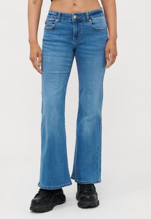 Lys blå flared jeans med knaplukning og fire lommer. Har en ren finish og syet detaljer langs sømmene.