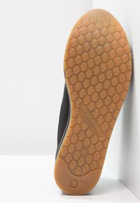 Mustan kengän pohja, jossa on kuusikulmainen kuviointi, kumimateriaalia. Vaaleanruskealla pohjalla on painettuna "VAGABOND SHOEMAKERS" ja merkitty koko "37".