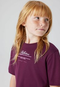 Czarnofioletowa bawełniana koszulka z białymi grafikami tekstowymi. Krótkie rękawy, okrągły dekolt i luźny krój. Miękka tekstura, minimalistyczny design.